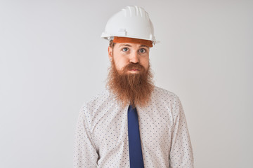 Young redhead irish architect man wearing security helmet over isolated white background puffing cheeks with funny face. Mouth inflated with air, crazy expression.