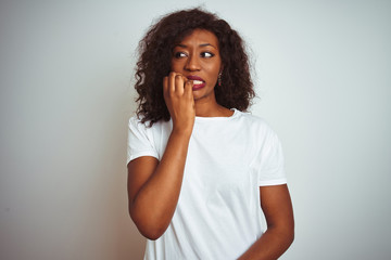 Fototapeta na wymiar Young african american woman wearing t-shirt standing over isolated white background looking stressed and nervous with hands on mouth biting nails. Anxiety problem.