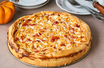 Quiche with pumpkin and tomatoes on a brown background