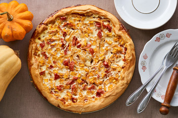 Quiche with pumpkin and tomatoes on a brown background