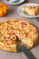 Quiche with pumpkin and tomatoes on a brown background