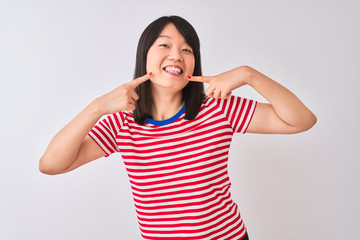 Obraz na płótnie Canvas Young beautiful chinese woman wearing red striped t-shirt over isolated white background smiling cheerful showing and pointing with fingers teeth and mouth. Dental health concept.