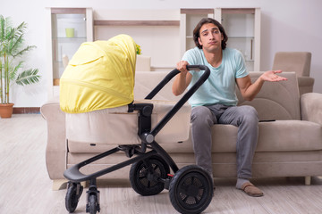 Young man looking after baby in pram