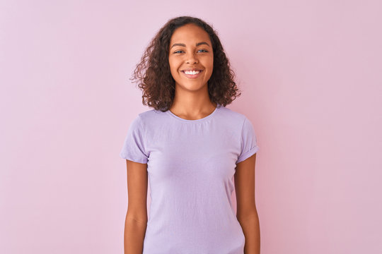 Young brazilian woman wearing t-shirt standing over isolated pink background with a happy and cool smile on face. Lucky person.