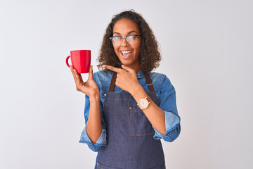 Brazilian barista woman wearing apron drinking cup of coffee over isolated white background very happy pointing with hand and finger