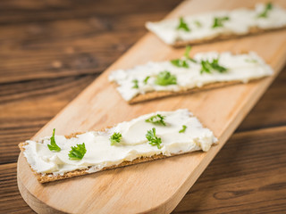 Bread toast with cream cheese and parsley on a cutting Board. Vegetarian snack.