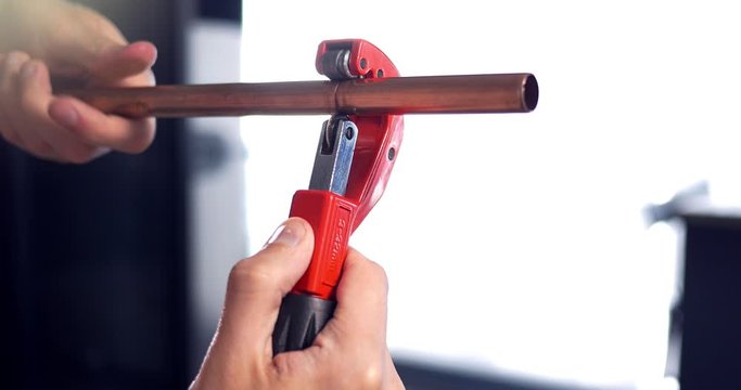 4K Plumber hand cutting Copper Metal Pipe. Man using cutter tool