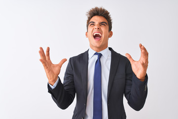 Young handsome businessman wearing suit standing over isolated white background crazy and mad shouting and yelling with aggressive expression and arms raised. Frustration concept.