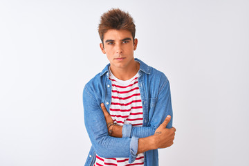 Young handsome man wearing striped t-shirt and denim shirt over isolated white background skeptic and nervous, disapproving expression on face with crossed arms. Negative person.