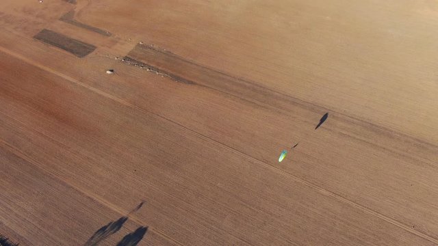 Drone aerial shot of paramotors flyingin over the empty wide field