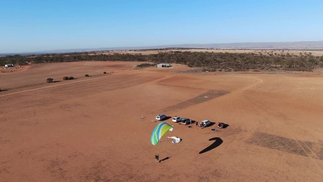 Wide aerial view tracking powered paragliding takeoff and flying in the air 