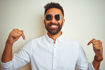 Handsome indian buinessman wearing shirt and sunglasses over isolated white background looking...