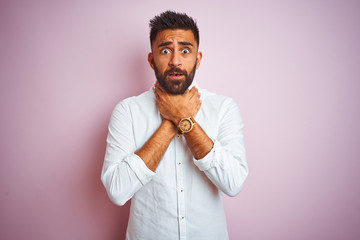 Young indian businessman wearing elegant shirt standing over isolated pink background shouting and suffocate because painful strangle. Health problem. Asphyxiate and suicide concept.