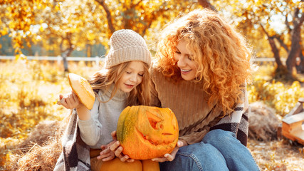 Young adult mother and daughter looking at carved pumpkin with smoke