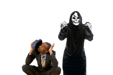 Man in a grim reaper halloween ghost costume having fun and scaring a grown businessman in a suit. ...
