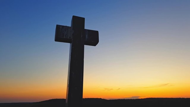 Stone cross on top of a mountain against a sunset. Cross on a sunset background. Stone crem on the mountain at sunset