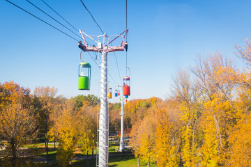 Autumn city landscape. Cableway in the park on blue sky background