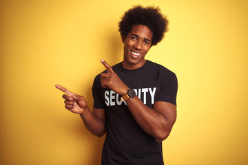 American safeguard man with afro hair wearing security uniform over isolated yellow background...