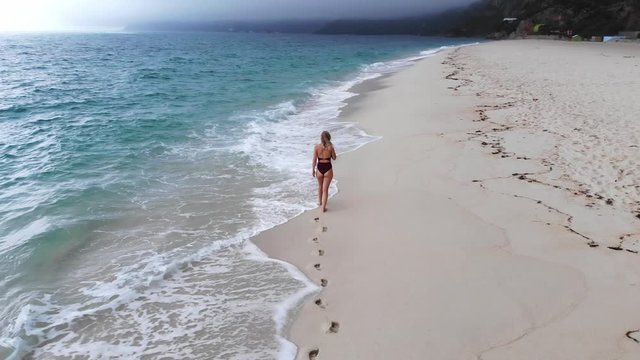Beautiful woman on an empty beach in paradise - aerial drone footage