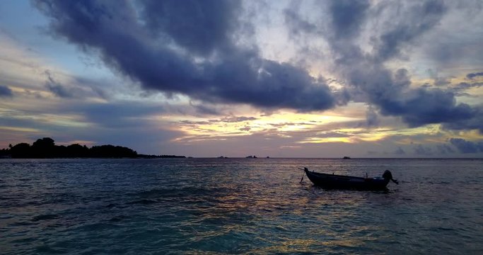 only one fishing boat floating in the tropical ocean on the early morning before sunrise. Dramatic sky with clouds