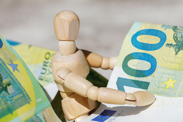 Wooden dummy puppet holding hundredth euro banknotes. Business concept