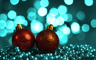 Two Christmas ornaments lying on balls of a Christmas chain on a blurred background with lights.