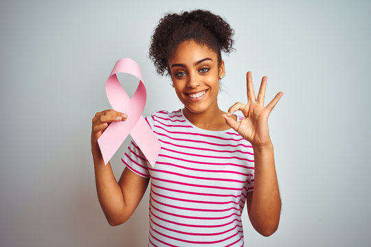 Young african american woman holding cancer ribbon over isolated white background doing ok sign with fingers, excellent symbol