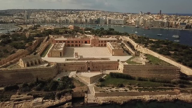 Aerial view fo Fort Manoel, Malta. Made famous by Game of Thrones and Assassin's Creed. Pull back shot front with city background.