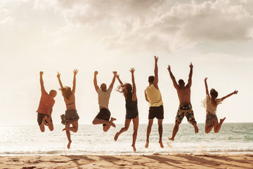 Happy friends jumps together at sea beach