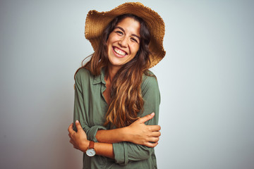 Young beautiful woman on vacation wearing green shirt and hat over white isolated background happy face smiling with crossed arms looking at the camera. Positive person.