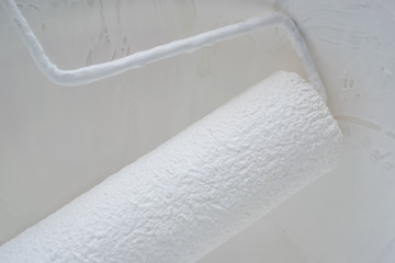 closeup of acrylic oil paint roller  on plaster wall texture background