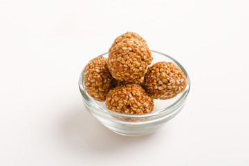 Indian sweet Sesame seeds ball or called in Hindi til ke laddu in glass bowl on white background 
