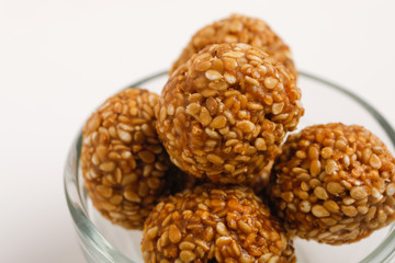 Indian sweet Sesame seeds ball or called in Hindi til ke laddu in glass bowl on white background 