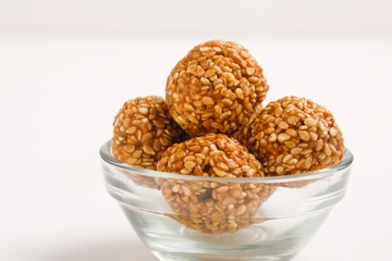 Indian sweet Sesame seeds ball or called in Hindi til ke laddu in glass bowl on white background 
