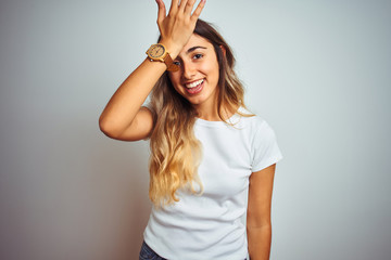 Young beautiful woman wearing casual white t-shirt over isolated background surprised with hand on head for mistake, remember error. Forgot, bad memory concept.