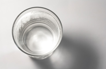 Top view of a clear glass of water with shadow on the bottom right