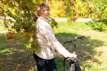 Fototapeta na wymiar A woman on a Bicycle rides through the autumn Park among the trees.