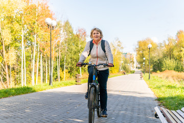 A woman on a Bicycle rides through the autumn Park among the trees.