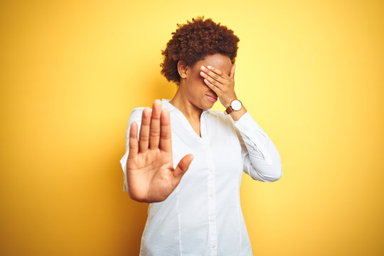African american business woman over isolated yellow background covering eyes with hands and doing stop gesture with sad and fear expression. Embarrassed and negative concept.