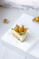 Passionfruit vegan cheesecake with Physalis on marble background with copy space