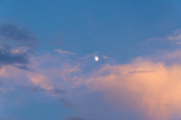 Incomplete moon in the sky during sunset at dusk.