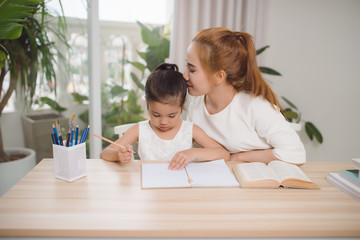 Asian mother and daughter doing home work together in living room