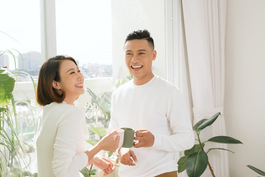 Young Asian Couple Drinking Coffee In Living Room At Home