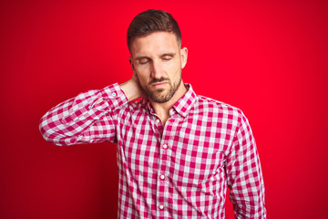 Fototapeta premium Young handsome man over red isolated background Suffering of neck ache injury, touching neck with hand, muscular pain