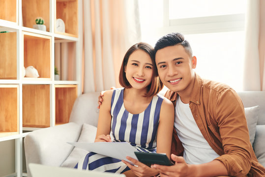 Young Asian Couple Checking Bills Using Laptop At Home