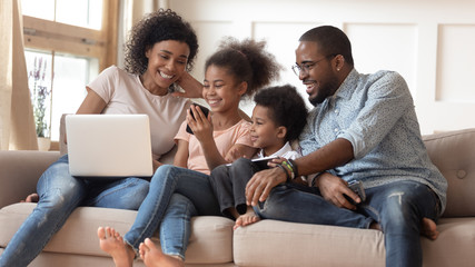 Smiling black family watch funny video on smartphone