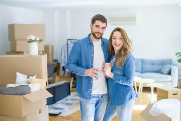 Fototapeta na wymiar Young couple relaxing from moving to a new house drinking a coffee around cardboard boxes