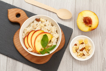 Sorghum salad with nuts and fresh peach on stone board.