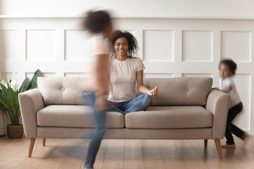Fototapeta premium Happy black mom practicing yoga with active kids around