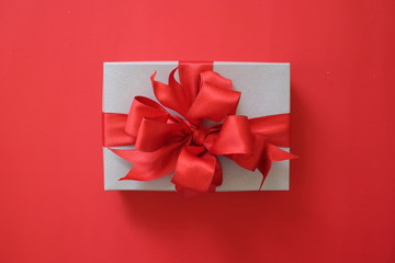 Silver gift box with red ribbon isolated on red background for giving in holidays. Holidays, present, giving concept. New year day, Christmas day, Chinese New Year day, Birthday.